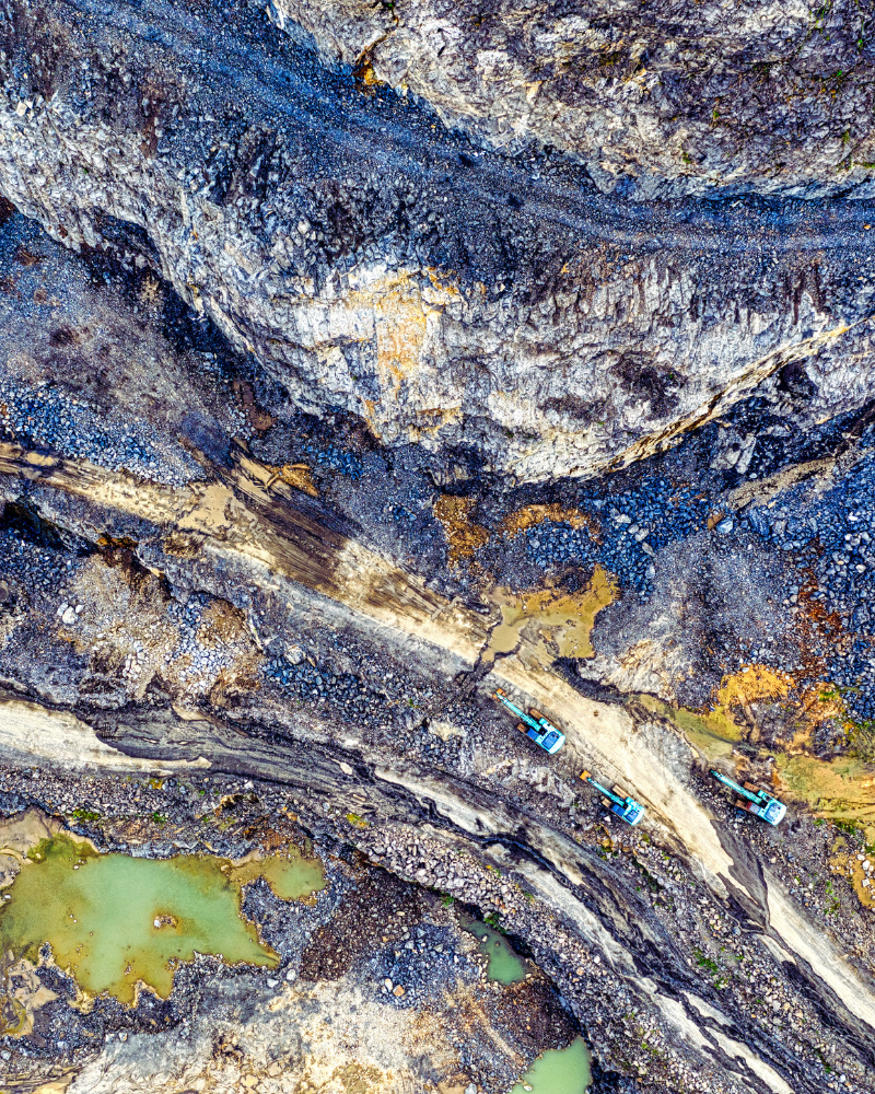 Birds-eye view of a mining site showing different substrates of rock and mining machinery