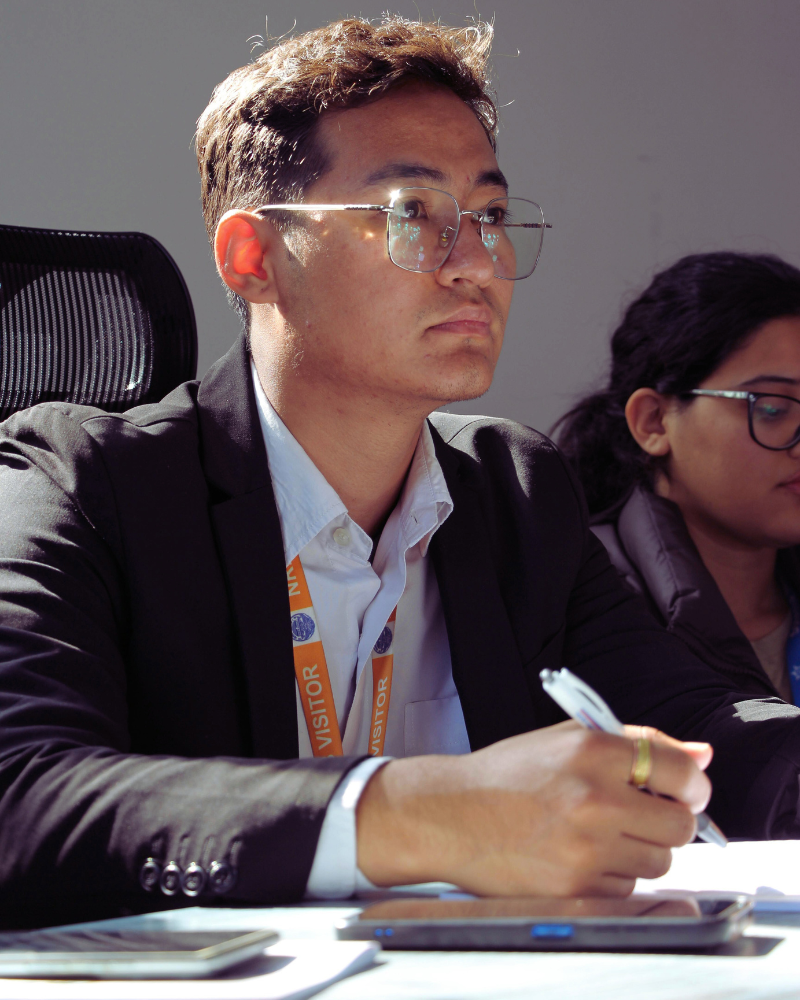 Person sitting at table looking at instructor with pen and paper in front of them